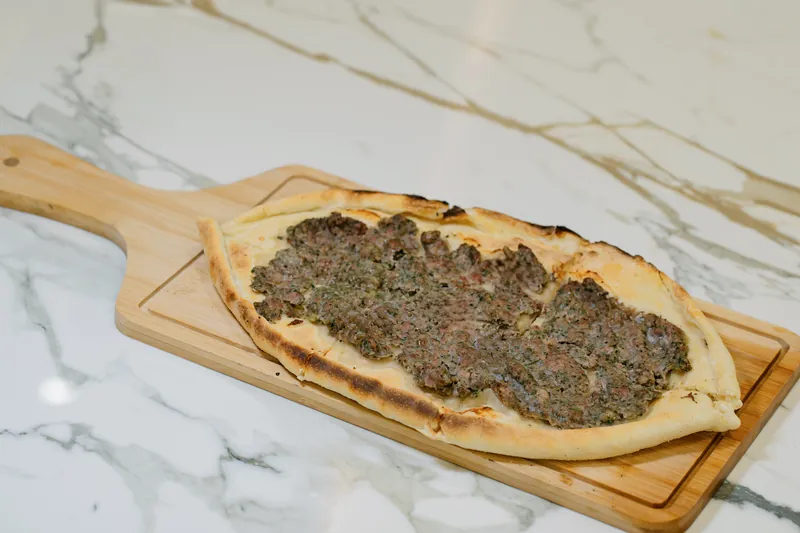 Pide à la viande hachée et aux herbes sur planche en bois